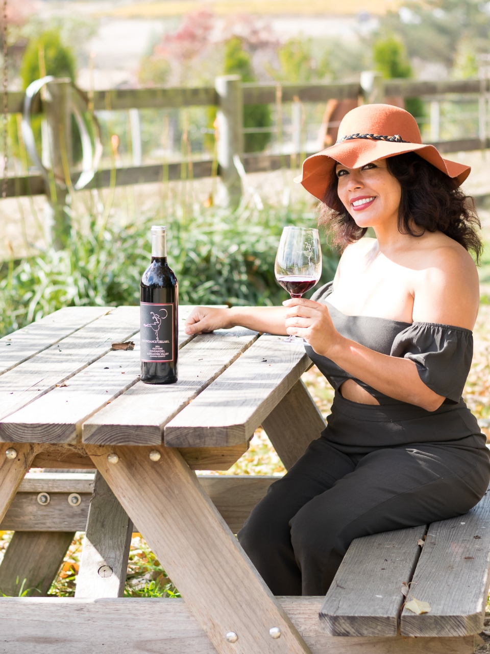 Frances Gonzalez with a glass of red wine at a vineyard — founder of Vegan Wines